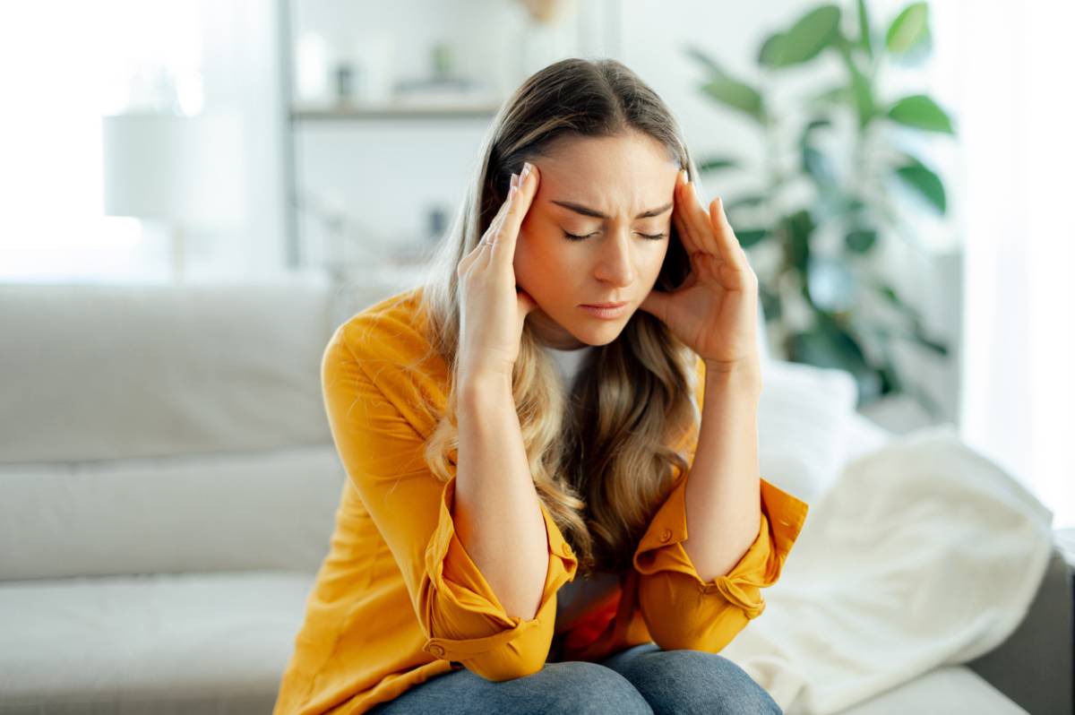 Woman pressing her fingers to her temples with a pained expression, having migraine